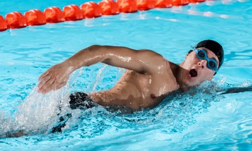 drops of water near athletic swimmer with opened mouth training in swimming pool